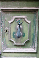 vintage bronze dolphin knocker on light green wooden door with keyhole, Mosta, Malta