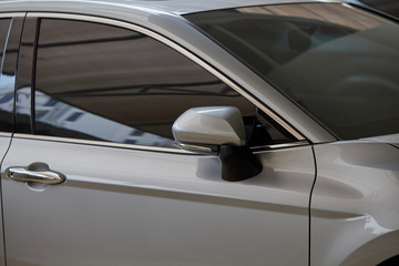  Rear-view mirror closed for safety at car park,  Rear-view mirror of gray car , black tinted glass. Close up of wing mirror of gray vehicle. Selective focus.