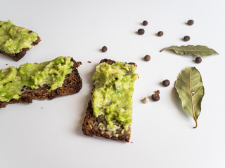 Avocado and bread. Avocado pate spread on slices of black bread. Spices and spices
