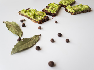 Avocado and bread. Avocado pate spread on slices of black bread. Spices and spices