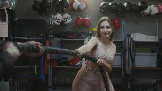 Elegant woman pulls rope with man