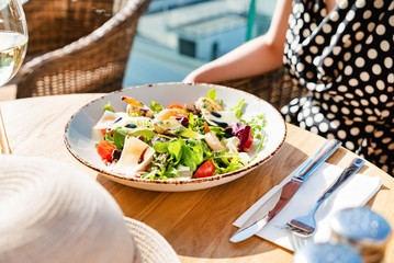 woman eating salad with shrimps on the summer terrace