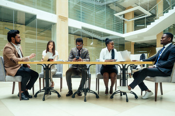 a group of successful afro americans, europeans ,arabic and korean businessman and businesswoman working in the office with large glass windows