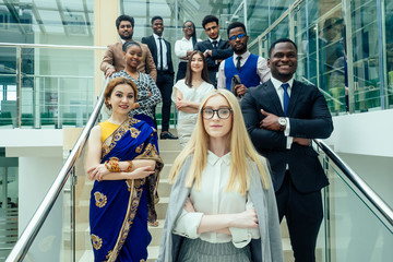 Multi Nationality of business people : indian, korean, afro-american and caucasian stand on the stairs in a modern office with panoramic windows.career enhancement concept