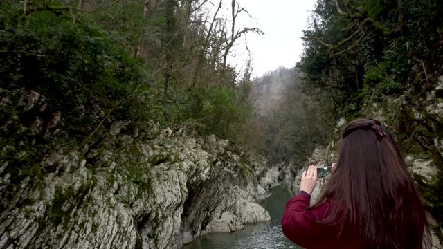 Travel concept. Woman making photos at Canyon Devil's Gate in Sochi, Russia.