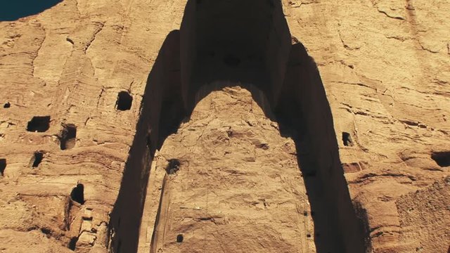 Wide tilt shot of the remains of the UNESCO World Heritage Buddhas of Bamyan Archaeological Remains after being dynamited by the Taliban in 2019