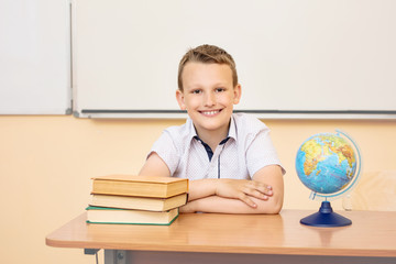 Boy child schoolboy happy, funny and cute with smile - portrait in classroom sitting at Desk