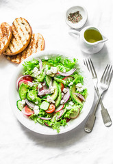 Vegetarian avocado, vegetables, feta cheese salad and grilled bread - delicious healthy lunch, snack on a light background, top view