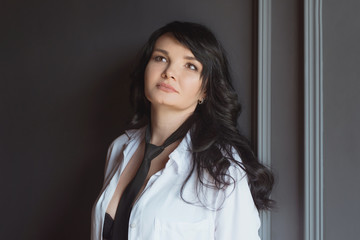 portrait of stylish, beautiful brunette woman with long hair in black bra and tie in white shirt and white pens