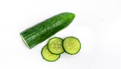 isolated on white sprinkled water background, fresh, green cucumber, next to slices of cucumber