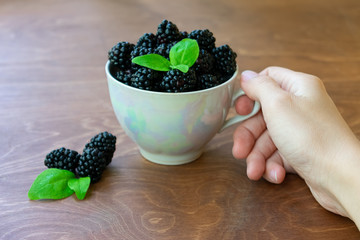 Cup full of blackberries on wooden background