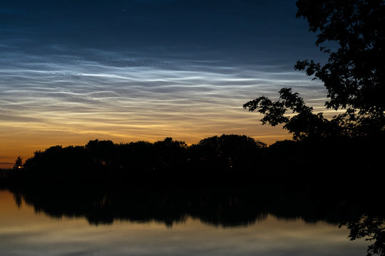 Bright  NLC, noctilucent clouds (shining night clouds) on the northern horizon near a lake close to Gouda, The Netherlands