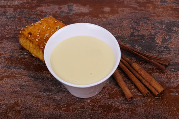 Condenced milk in the bowl with sinnamon and pastry
