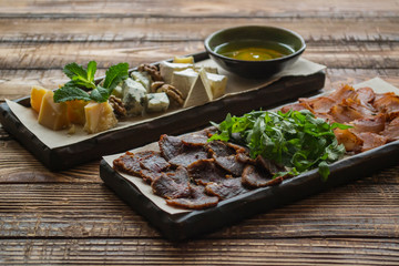 Cheese and meat plate on a wooden background.