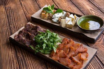 Cheese and meat plate on a wooden background.