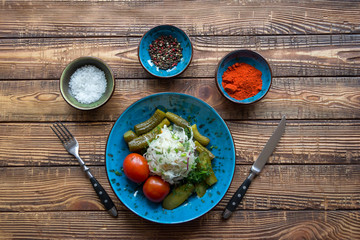 A bowl with pickles and spices on a wooden background.