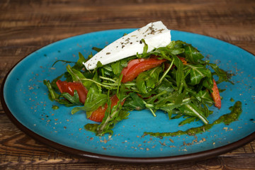 The salad with cheese and spices on a wooden table.