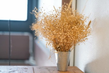 Beautiful dry grass flowers placed on a wooden table in the living room.