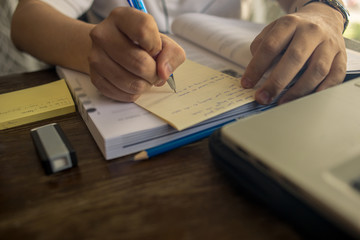 Close up of student hand writing sticky note while studying