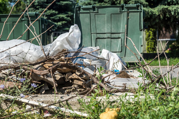 Big plastic dumpster garbage can full of overflow litter polluting the street in the city with junk and waste on the ground and grass 