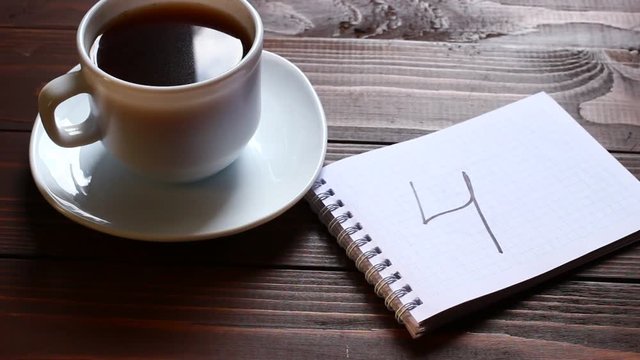 4 inscription and word in a notebook near a cup of coffee