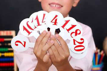 The concept of education, childhood and school  the child is studying the numbers and calculations at school. The boy holds the numbers in his hands. Cute preschooler boy teaches math.  Back to school