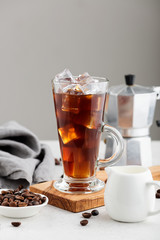 Summer drink iced coffee or caffe latte in a glass with milk and coffee beans.