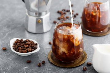 Summer drink iced coffee or caffe latte in a glass with milk and coffee beans.
