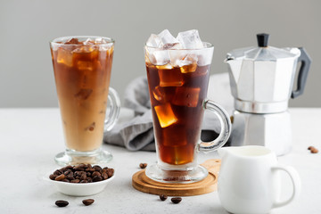 Summer drink iced coffee or caffe latte in a glass with milk and coffee beans.