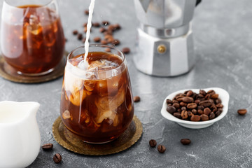 Summer drink iced coffee or caffe latte in a glass with milk and coffee beans.