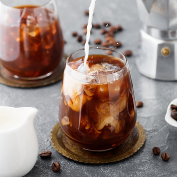 Summer drink iced coffee or caffe latte in a glass with milk and coffee beans.
