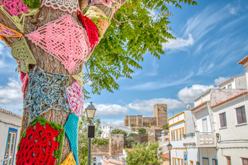 Trees decorated with colorful crochet patchwork on a holiday in the town of Mertola, a very...
