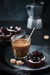 Coffee and chocolate cake with berries on a dark plate. Breakfast, coffee and dessert