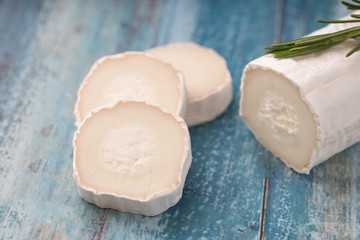 Fresh goat cheese with slices on paper.