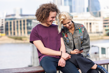 Happy couple talking sitting near River Thames.