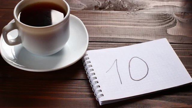 10 inscription and word in a notebook near a cup of coffee