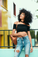 Smiling mixed woman with afro hair standing on the street