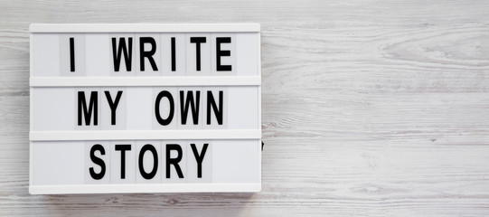 'I write my own story' words on a lightbox on a white wooden background, top view. From above, overhead, flat lay. Copy space.