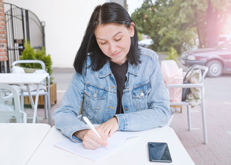 Young woman-freelancer taking notes about mathematics and statistics at coffee shop in selective focus. Business job offer, financial success, Student learning, Freelancer working.