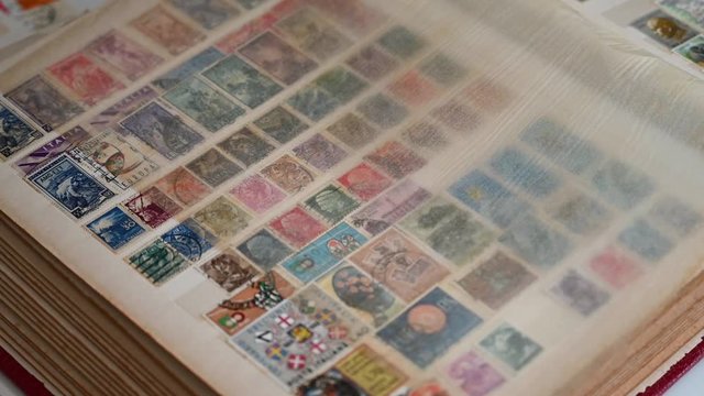 young girl's hand scrolls through an album of postage stamps