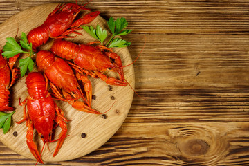 Boiled crayfish on cutting board on wooden table. Top view