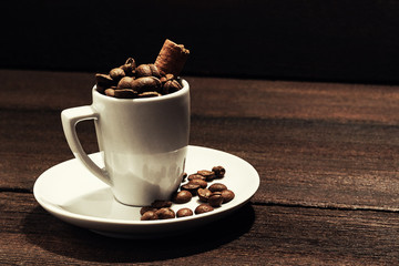 coffee cup of coffee beans with cinnamon on wooden background