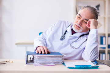 Fototapeta premium Old male doctor working in the clinic 
