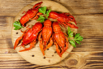 Boiled crayfish on cutting board on wooden table. Top view