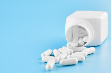 Pills tablets capsules closeup. On a blue background, a jar of medicine.