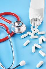 Pills tablets capsules closeup. On a blue background, a jar of medicine. On a blue background, a jar of medicine and a stethoscope.