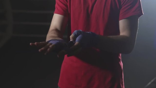 Man boxer wapping hands getting ready for fight in slow motion. Kickboxer prepare for training. Close-up view