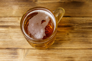 Mug of beer on a wooden table. Top view