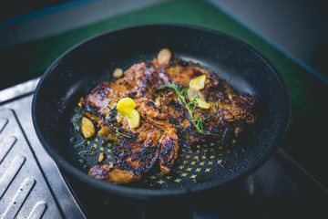 Cooked beef steak with rosemary and garlic inside iron skillet