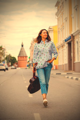 woman with a guitar smiles and goes along the road